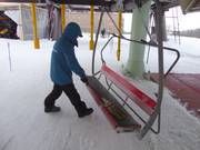 Der Sitz wird am Einstieg mit einem Besen von Schnee freigefegt
